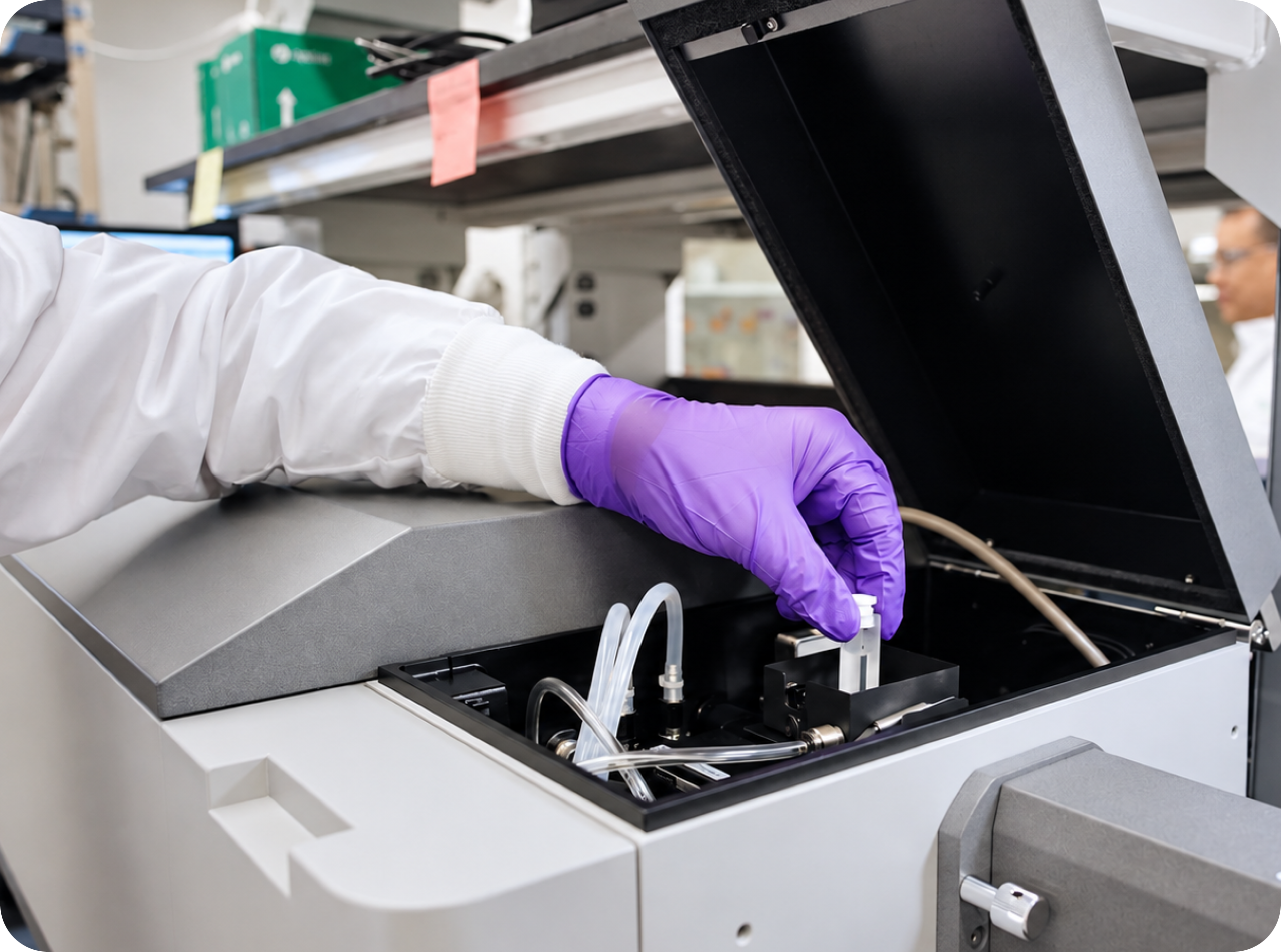 A gloved technician loading a sample into analytical laboratory equipment