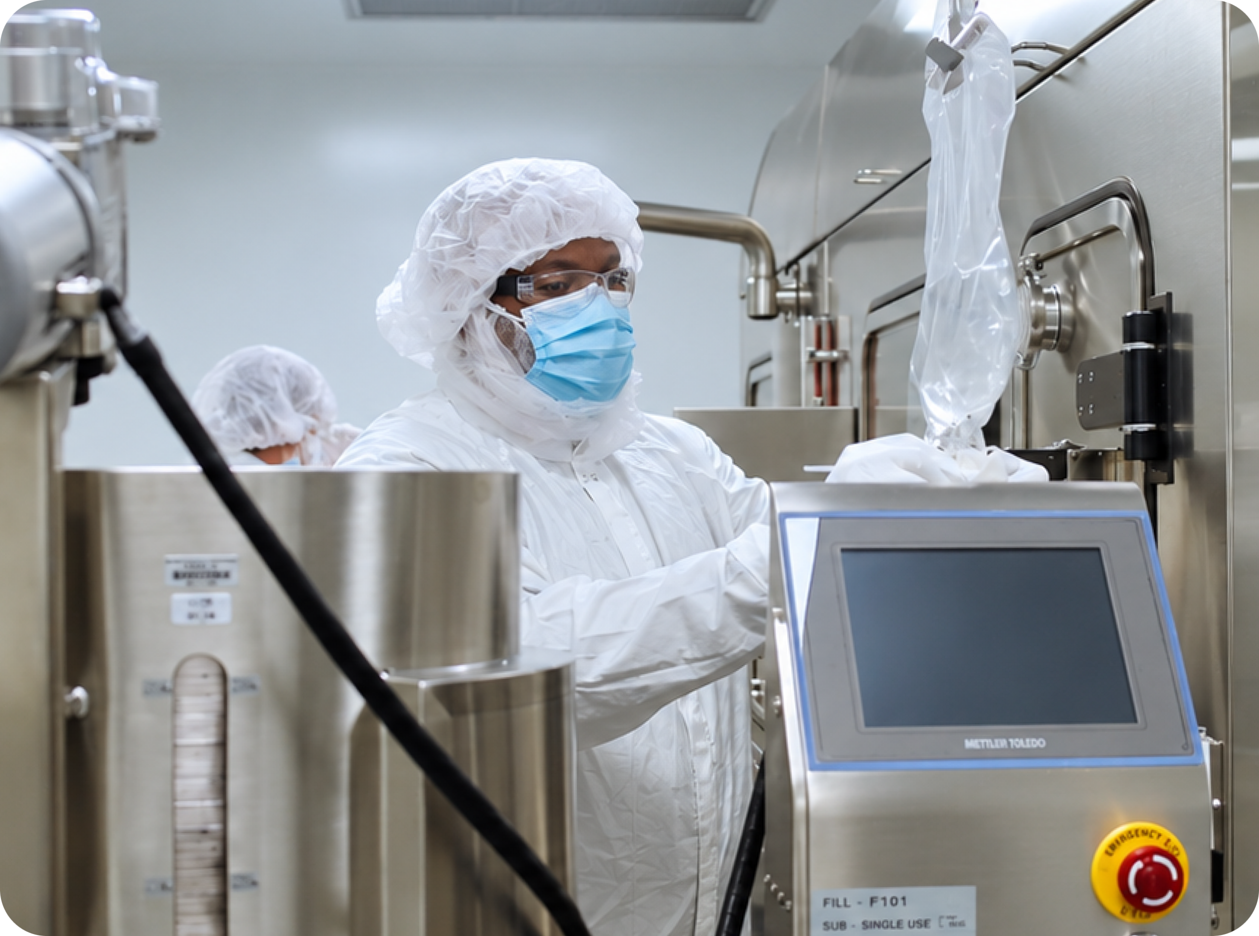 A technician operating pharmaceutical manufacturing equipment in a cleanroom